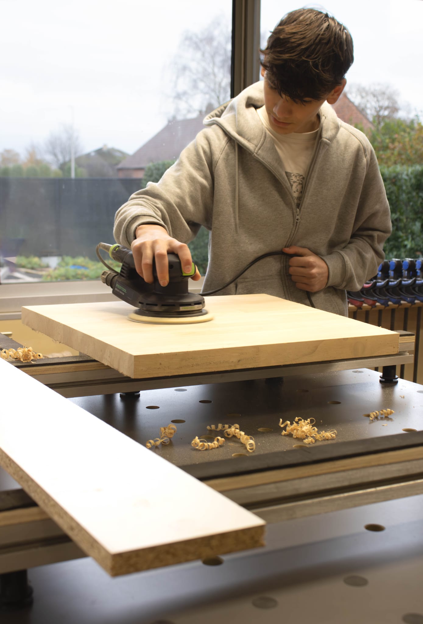 Zaakvoerder aan het werk in het atelier, schurend aan een houten paneel