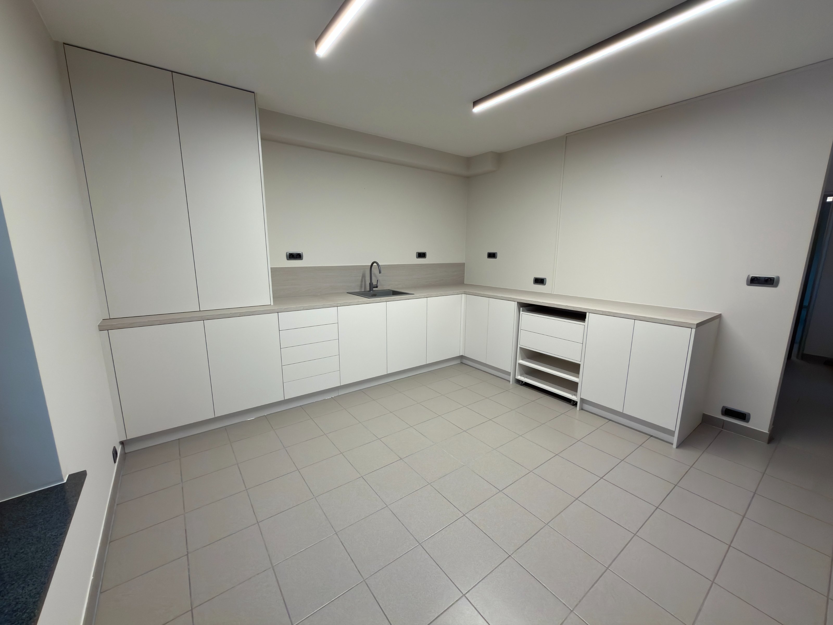 Volledige kastopstelling op maat in een bijkeuken: witte greeploze kasten met werkblad in grijs houtdecor