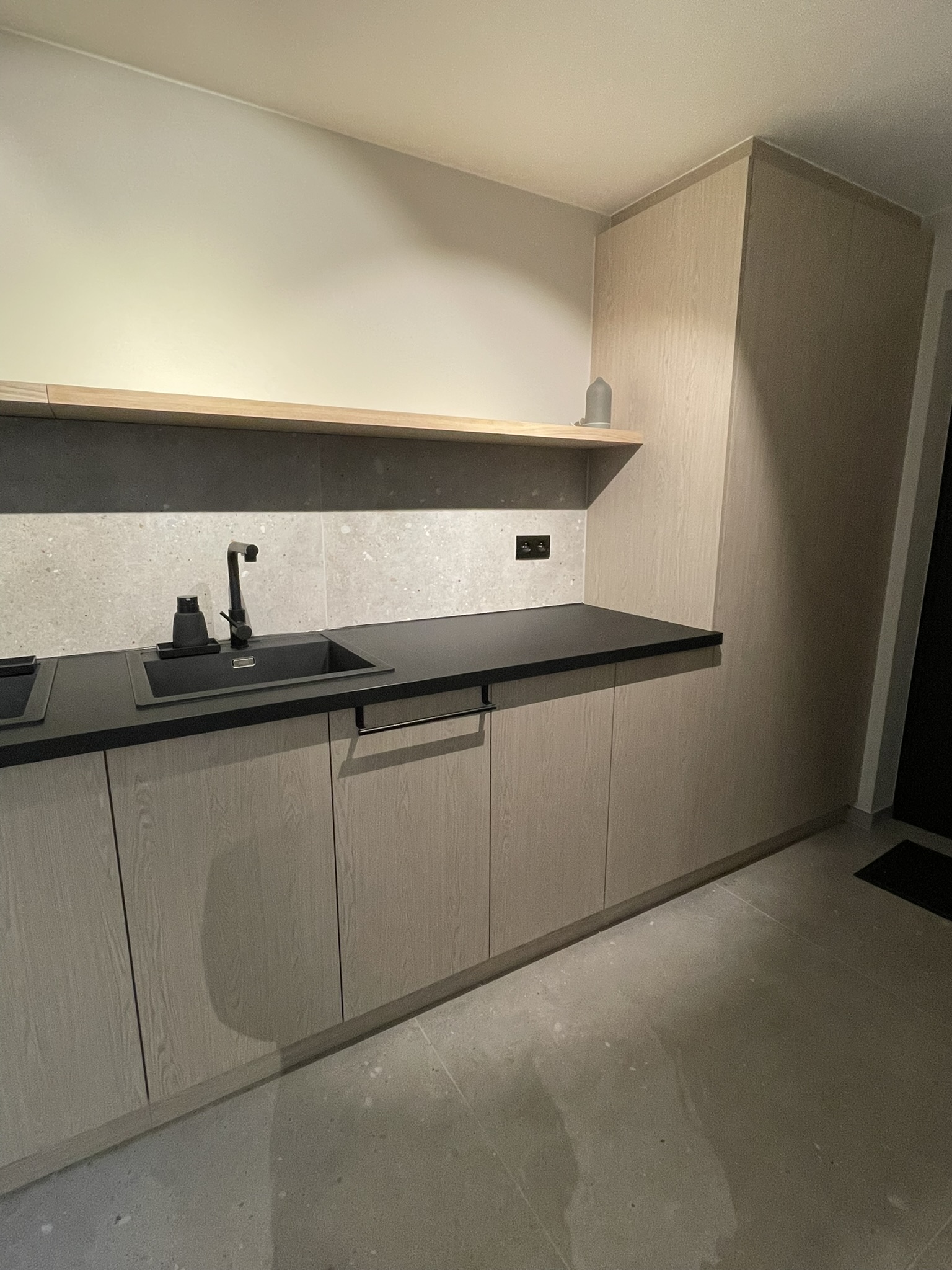 Greeploze kastenwand in houtdecor met zwart werkblad, van muur tot muur