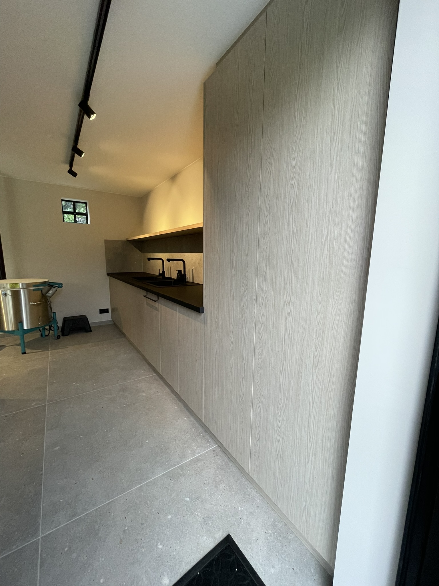 Hoge kastenwand met greeploze fronten in melamine houtdecor, van vloer tot plafond