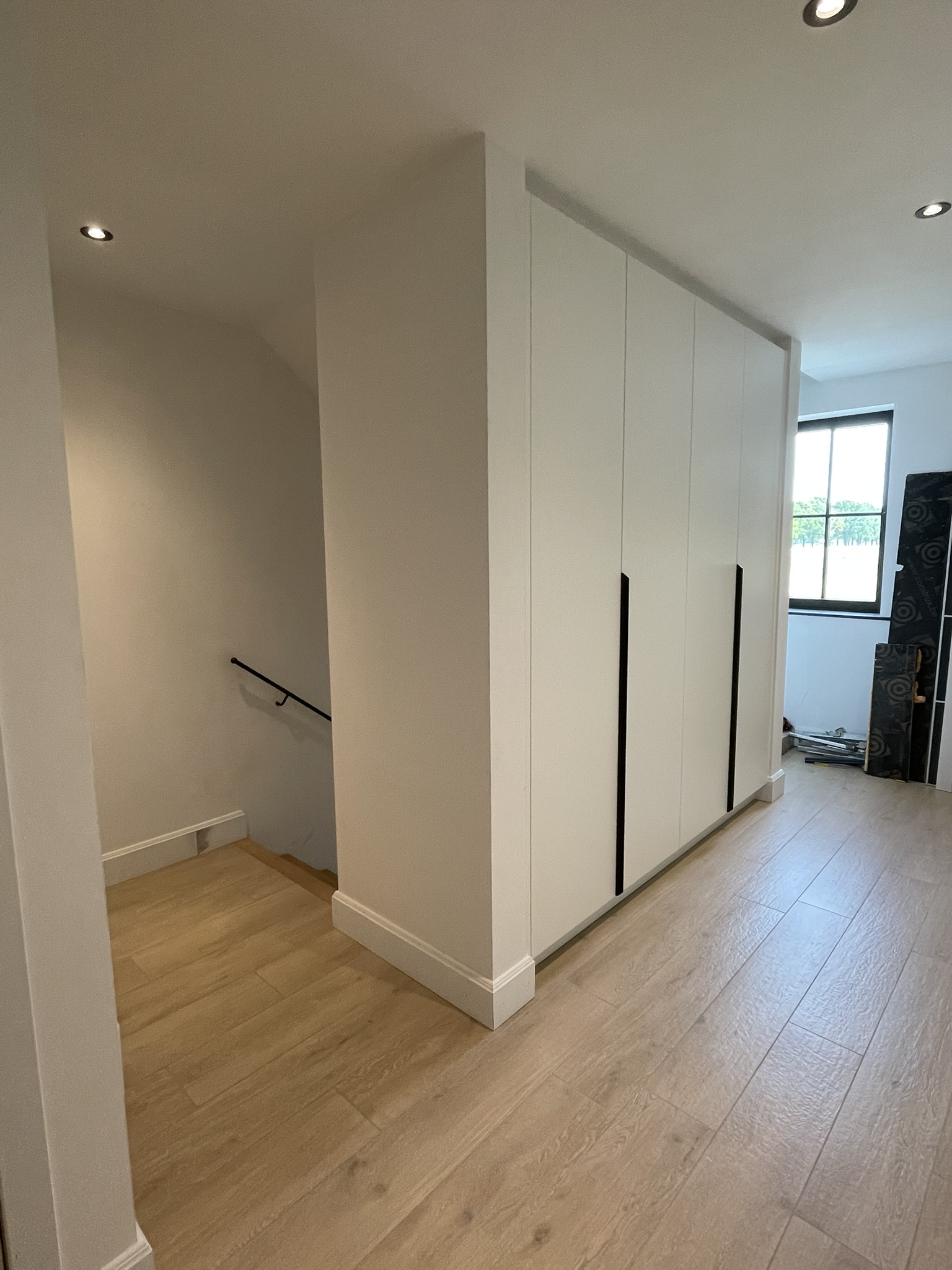 Fronten met lange zwarte grepen van de gangkast in witte melamine