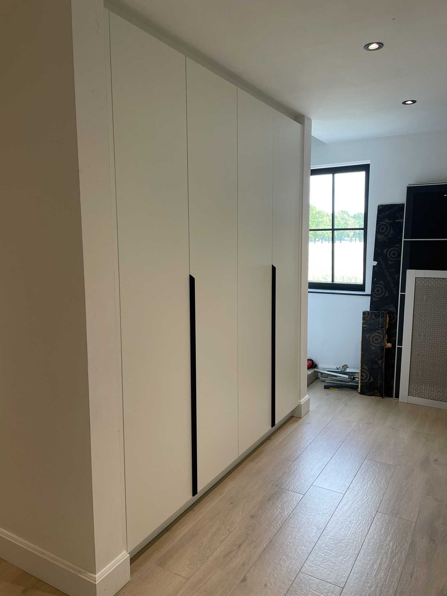 Witte gangkast met lange zwarte grepen over de volledige wand